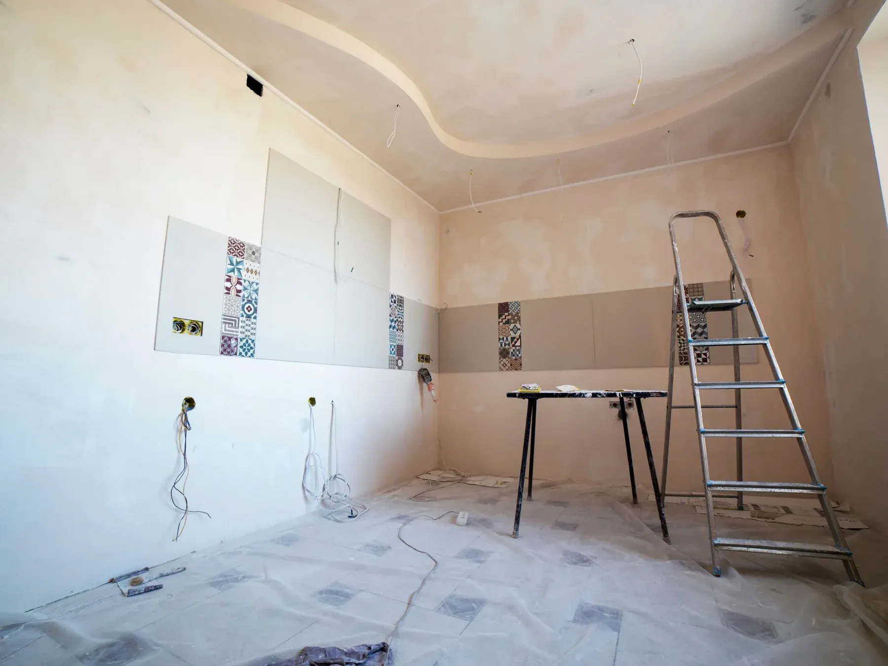 A bright interior partway through renovation, with unfinished walls, exposed fittings and a work ladder.