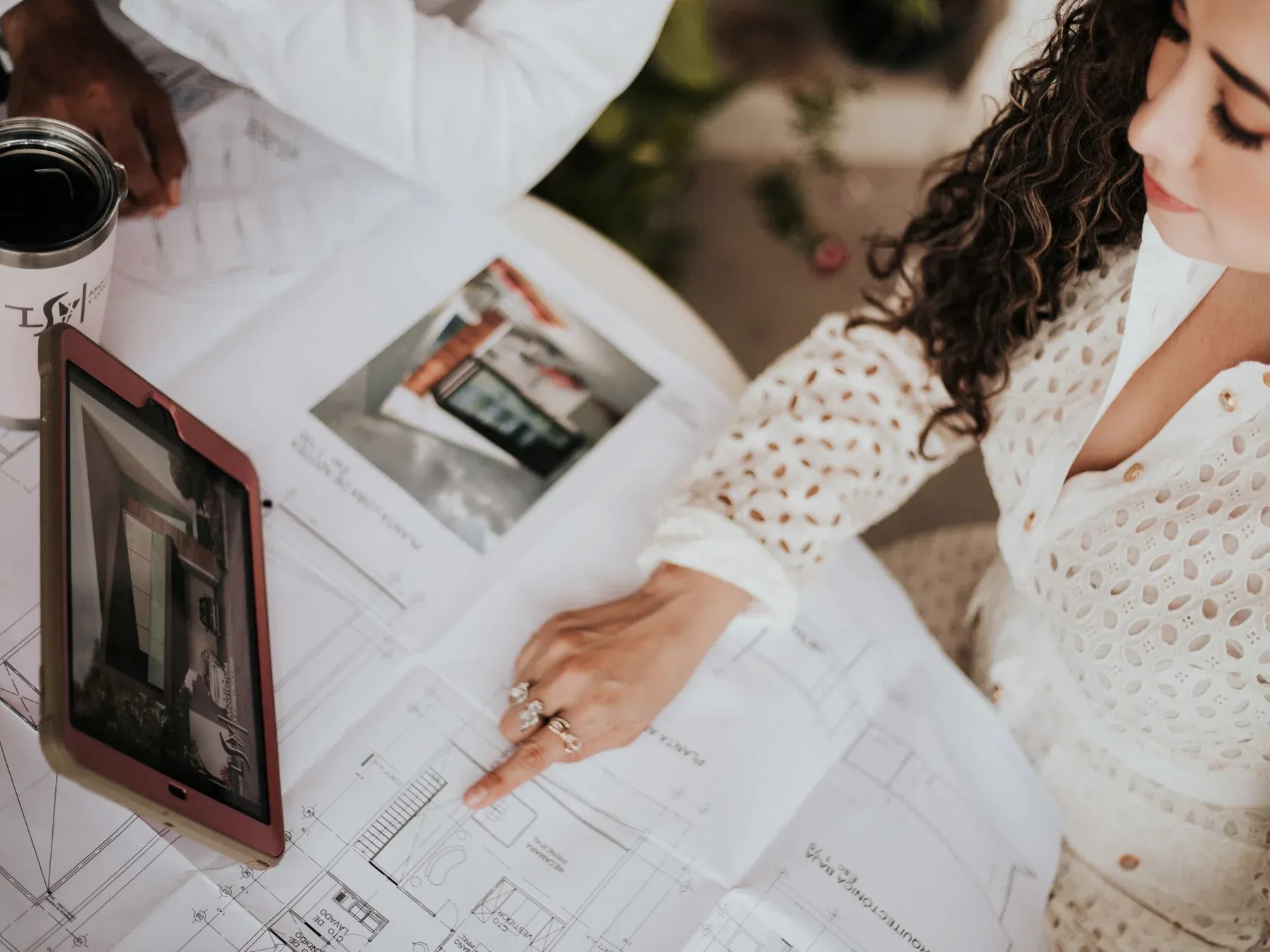 Two people coordinating a renovation over architectural plans, reference photographs and a tablet.